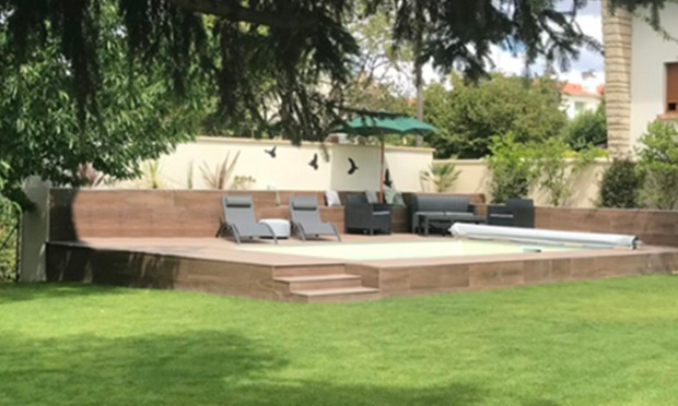Terrasse surélevée de la piscine vue depuis la pelouse
