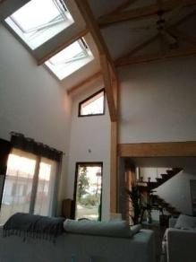 Séjour sous charpente apparente avec fenêtres de toit et escalier bois